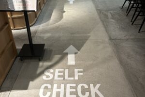 館内に入ると、床面に「セルフチェックイン」の文字と矢印表示がございます。 　矢印に沿って、チェックイン機までお進みください。